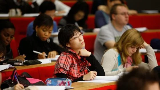 student sitting in a lecture theatre taking notes