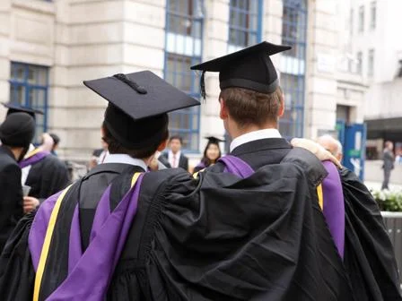 Two male graduates at graduation with their backs to the camera positing for a photo