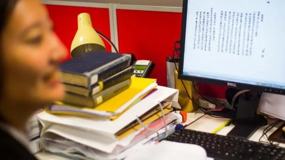 Student at desk with screen and books