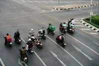 A group of people on motorbikes waiting at a crossroads