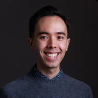 Nicholas Pang, he is smiling against a grey backdrop.