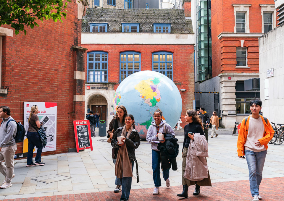 Students walking on campus in front of "The World Turned Upside Down" sculpture.