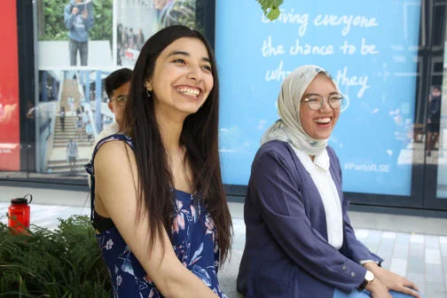 PhD students next to the posters on the outside of St Clement's Building on LSE Square.