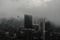 A bird-eye view of tall buildings in Jakarta shrouded in dark clouds.
