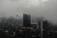 A bird-eye view of tall buildings in Jakarta shrouded in dark clouds.