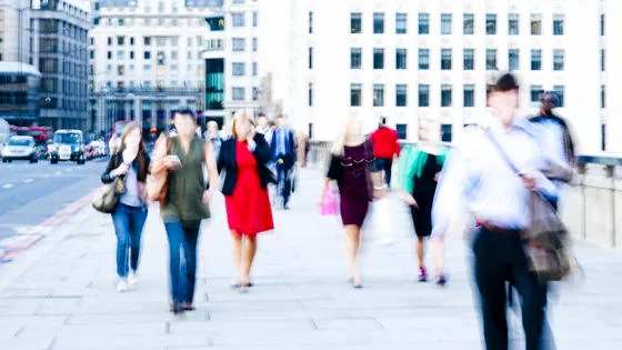 A blurred image of commuters walking in a city.