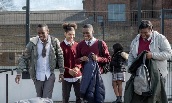 Young men in school uniform walking and smiling