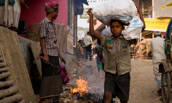 A boy carrying a bag on his head.