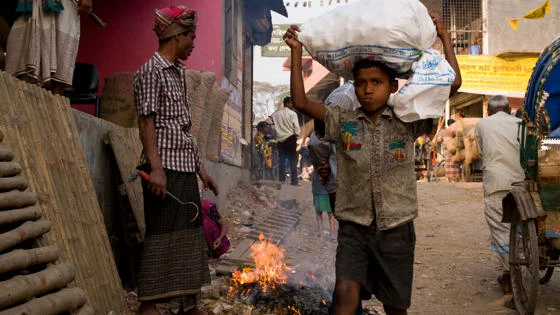 A boy carrying a bag on his head.