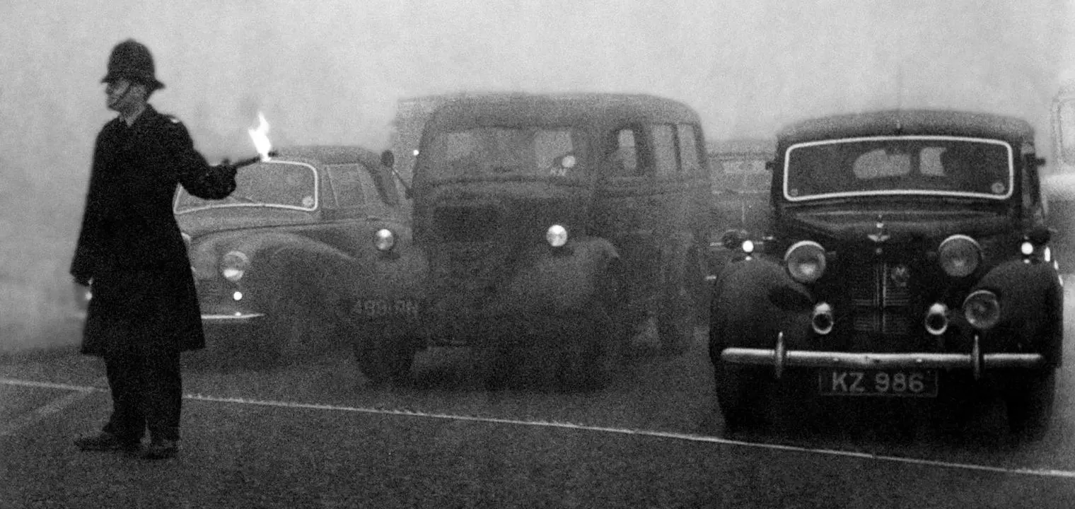 Policeman guides traffic with flare in London's Great Smog, 1952