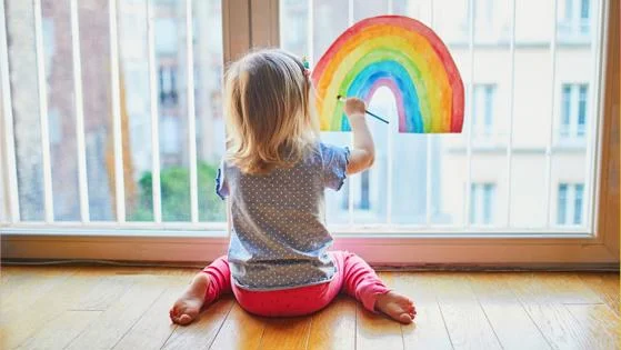Child painting rainbow on window