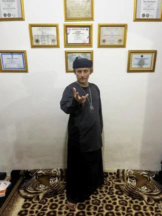 hpynosis practitioner standing by wall of certification