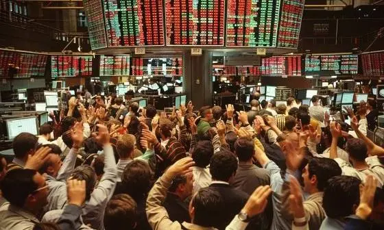 Crowd of traders on a trading floor, staring at electronic boards and gesticulating