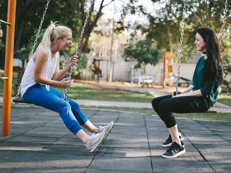 Two people on swings facing one another