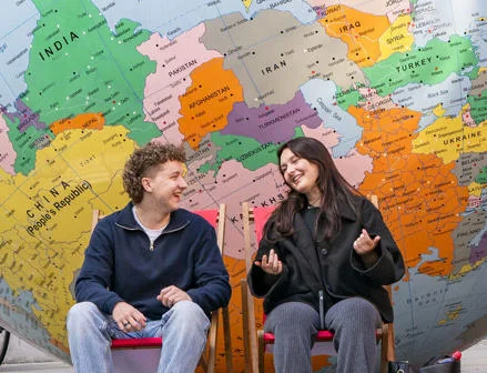 Two students sitting in front of LSE's globe