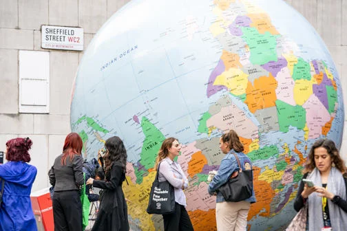 A group of people next to the LSE globe