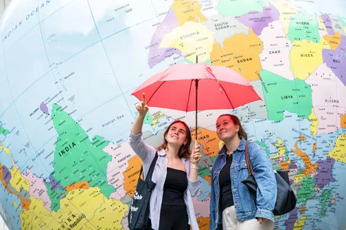 two girls stranding in front of globe