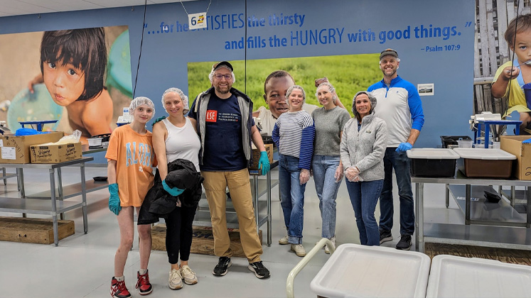 Alumni gather for a photo after helping in a community kitchen for Global Day of Volunteering