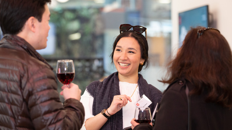 A woman chats to two fellow alumni over wine in the Alumni Centre