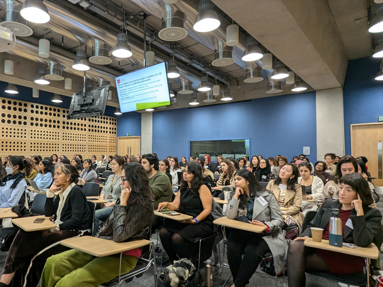 A large lecture hall is full of women listening to a panel discussion during the launch of LSE's Women's Alumni Network