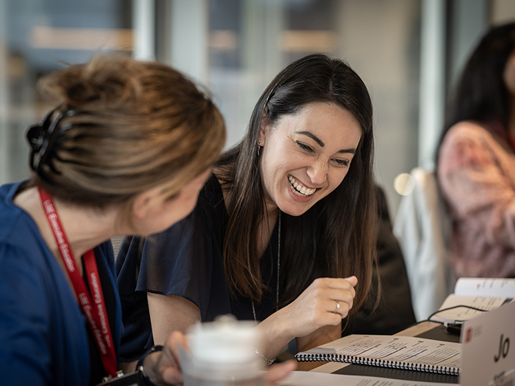 Three students, with one woman smiling as she looks at paperwork.