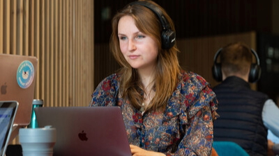 Woman working on a laptop and wearing headphones