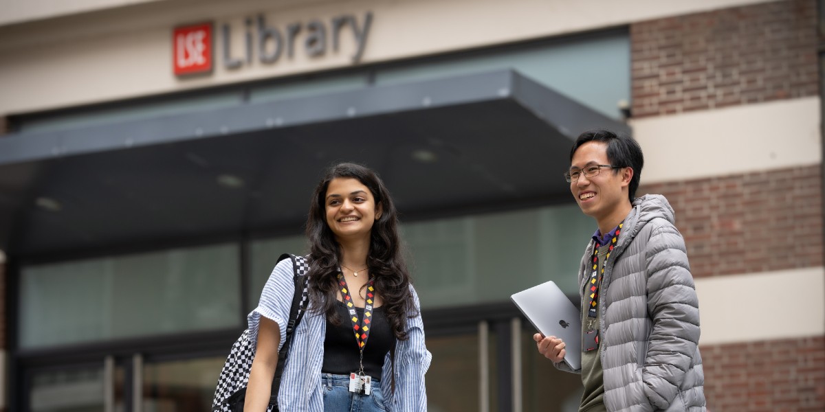 Two people stood outside LSE Library smiling