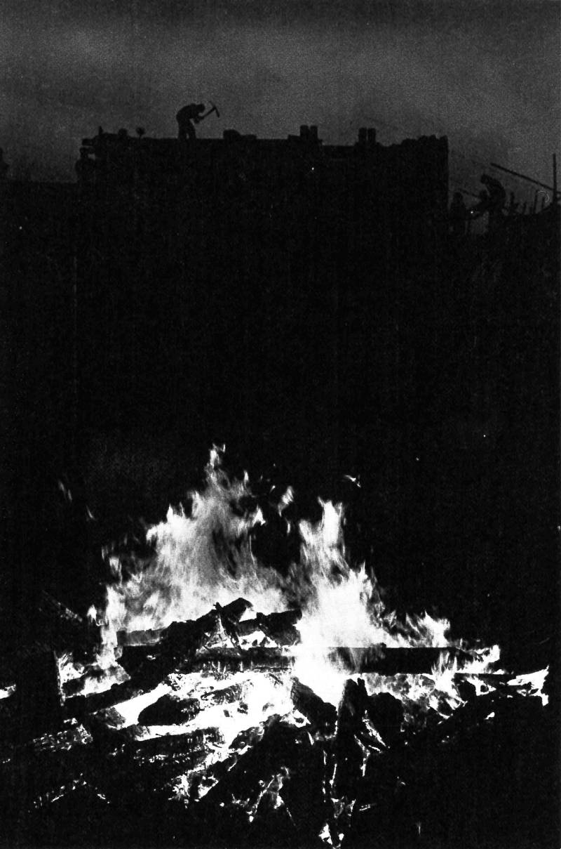 A fire in the foreground and people mining (?) in the background