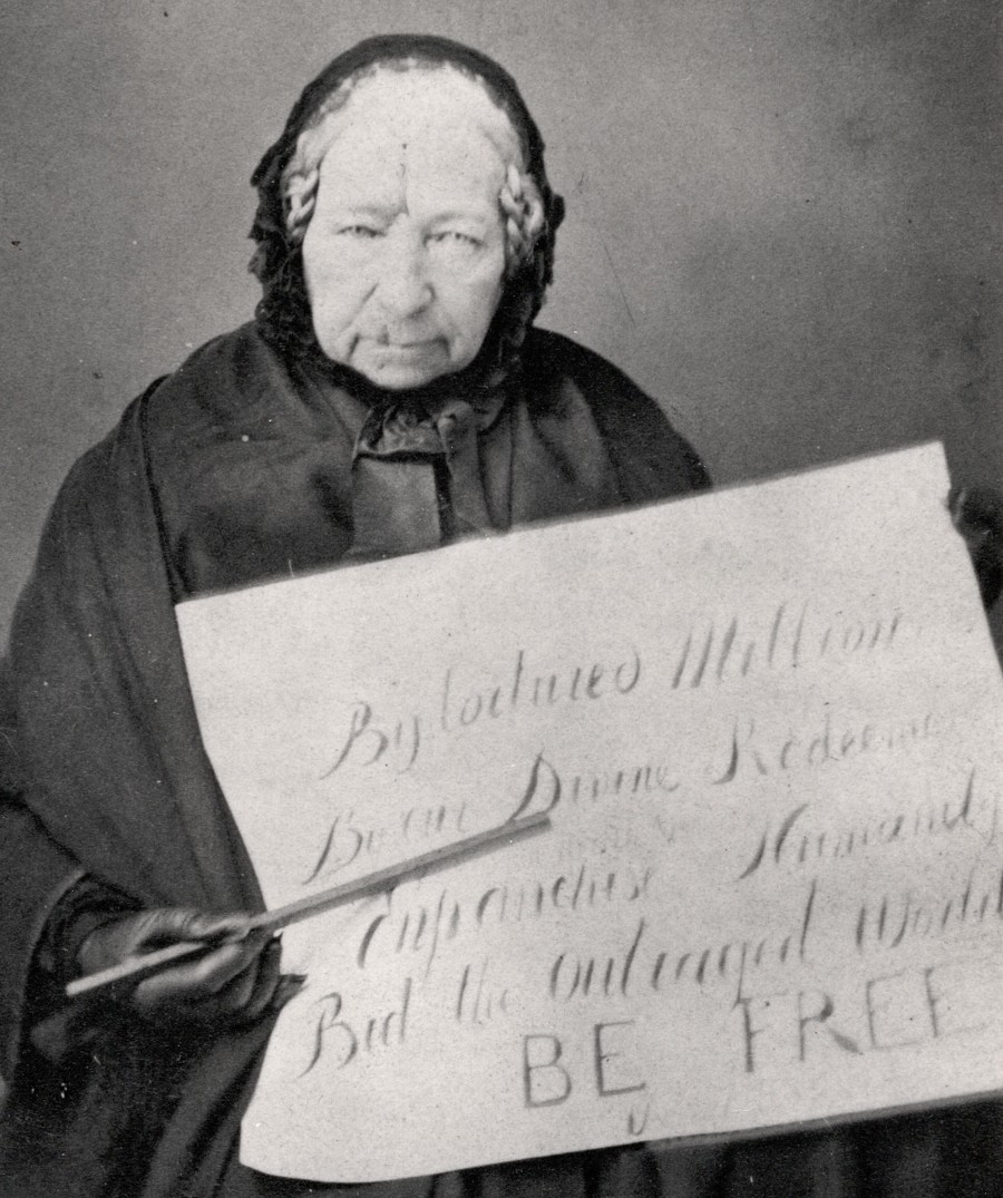 A portrait of Anne Knight holding up a placard/poster.