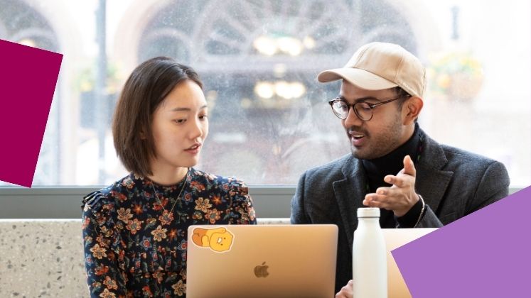 Two students working on a shared laptop.