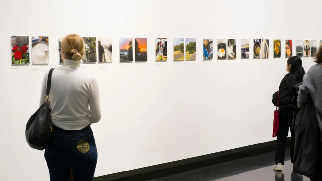 People looking at exhibition of photographs about life during a cost of living crisis