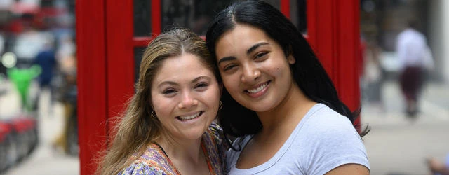 Two Summer School students standing in front of a red telephone booth.