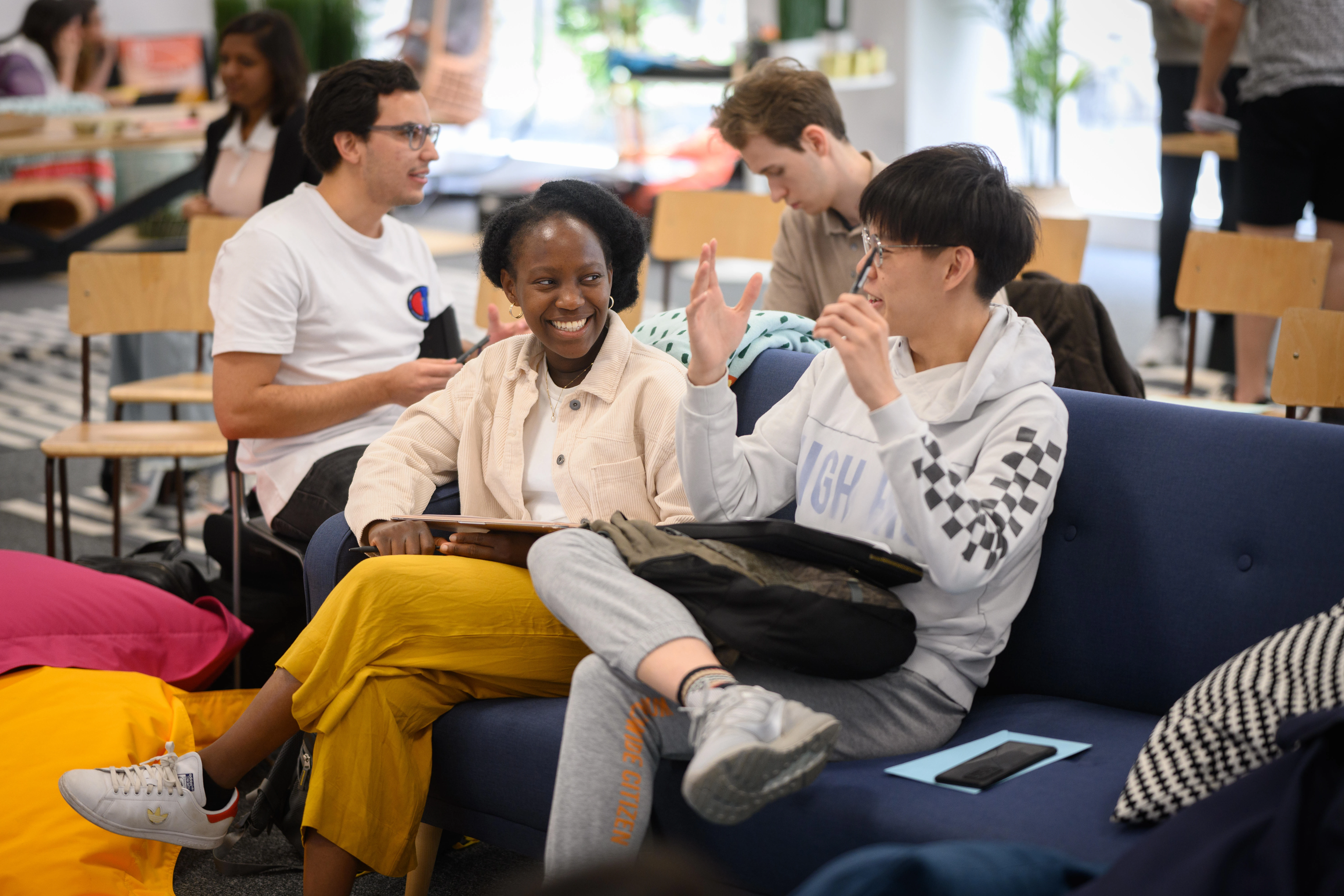 Two students in conversation sat on sofa in GenDen